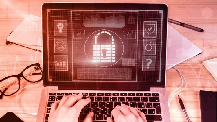 Close-up of hands using a laptop that displays a digital padlock on the screen, symbolizing cybersecurity and data protection.
