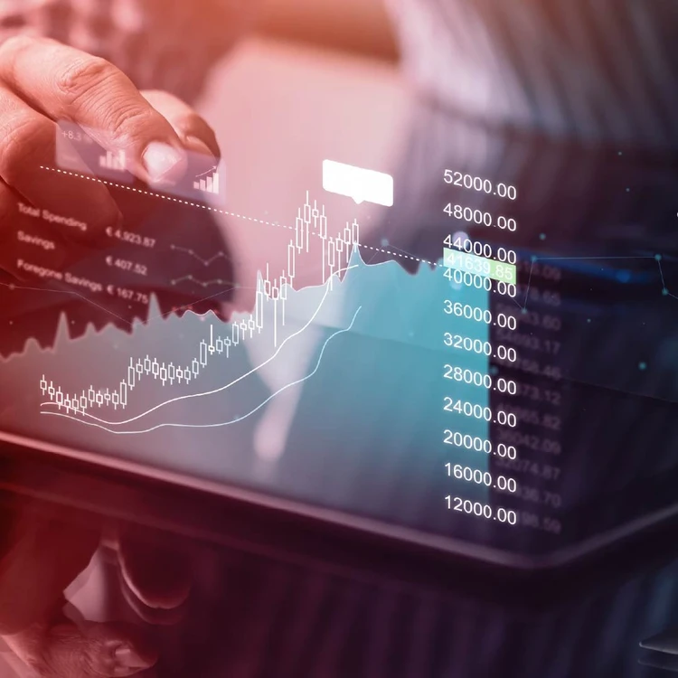 Hands holding a tablet displaying financial charts and data, with curves and candlesticks indicating market analysis.